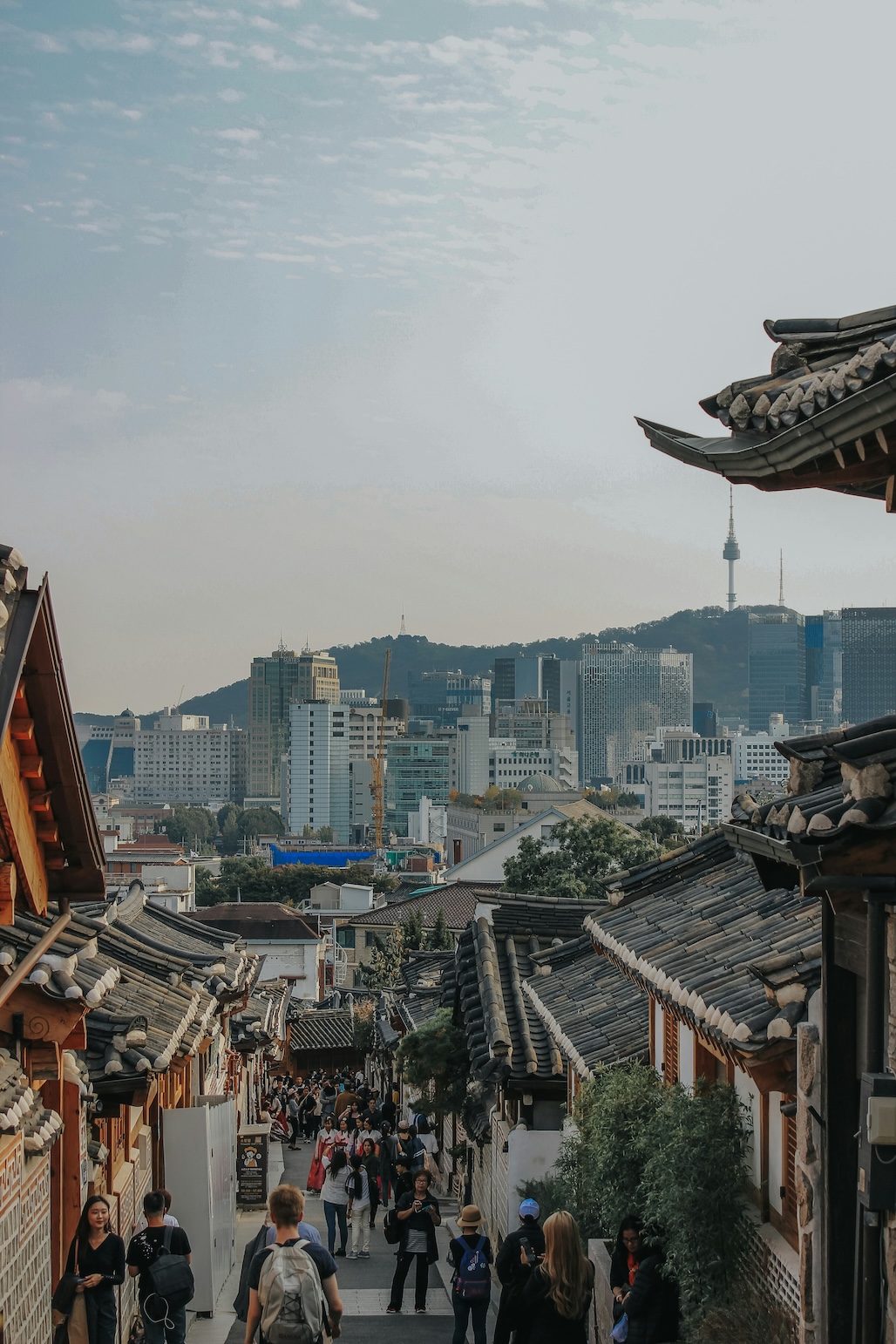 Traditional Korean hanok village with Seoul skyline in background